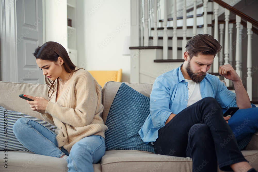 Portrait of young couple standing back to each other and looking at the phone. Portrait of young couple standing back to each other and looking at the phone.