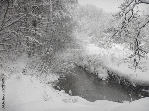 Winter forest landsacape with the river and snowflakes  photo