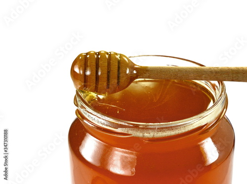 Jar with organic honey isolated on white. Glass jar full of honey and dipper isolated on white background.