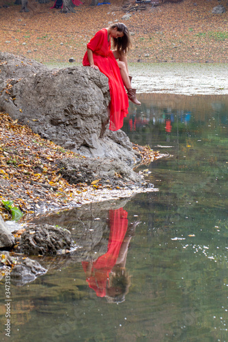 woman in the autumn forest. fairy-tale reflection in the lake. Fashionable woman standing over lake in park.