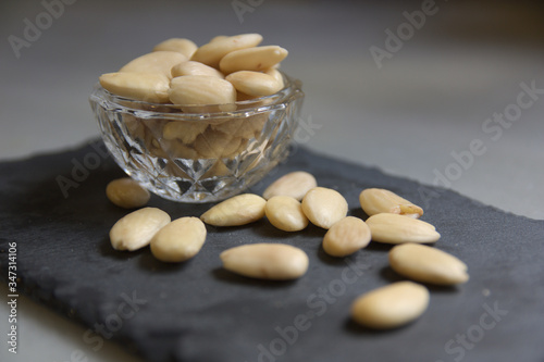 Closeup of a glass bowl with peeled almonds on a neutral background