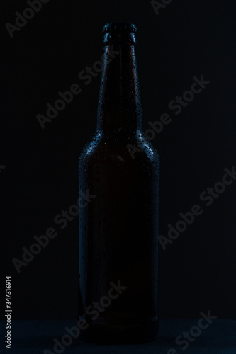 beer bottle with drops drink without label on a dark background