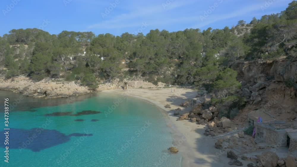 Aerial Drone forward view of paradise white beach and turquoise water with couple walking, Ibiza, Spain Aerial Drone forward view of paradise white beach and turquoise water with couple walking, Ibiza, Spain