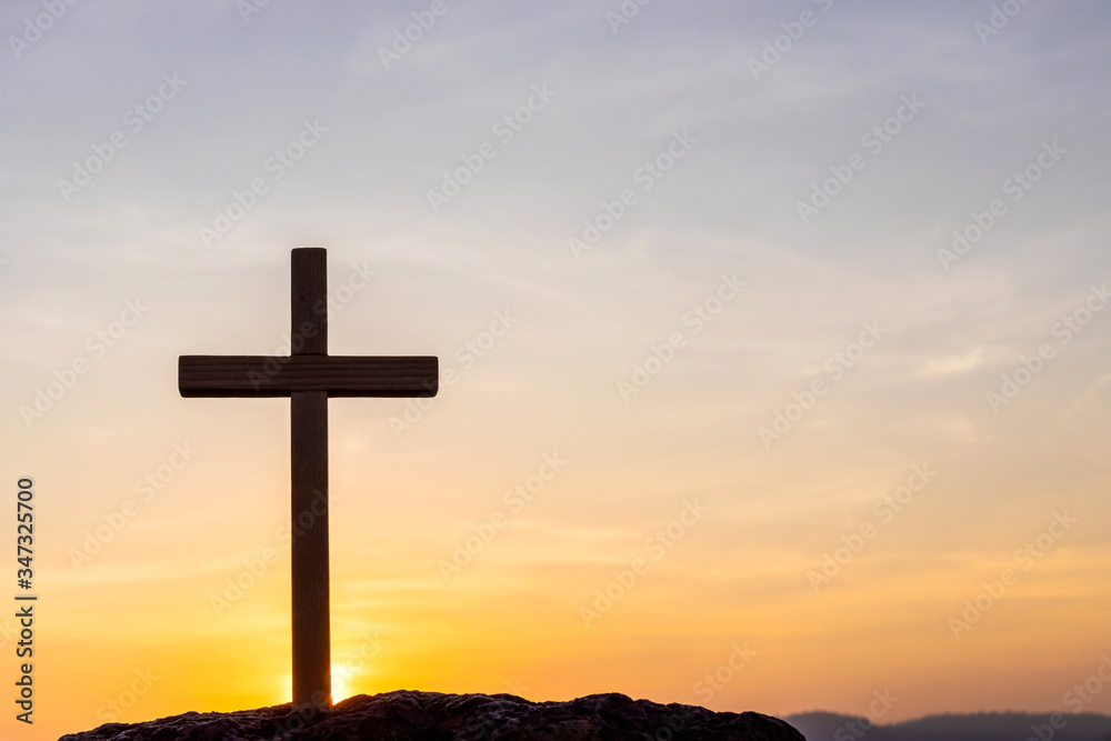 Silhouettes of crucifix symbol with bright sunbeam on the colorful sky background