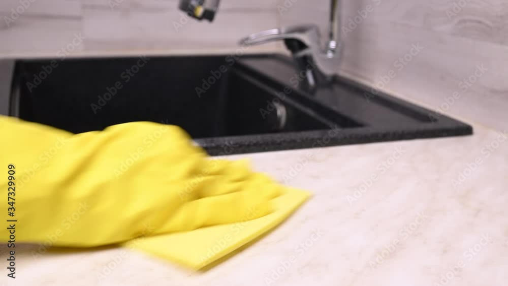 A woman disinfects the kitchen surfaces and sink during a outbreak covid-19 A woman disinfects the kitchen surfaces and sink during a outbreak covid-19