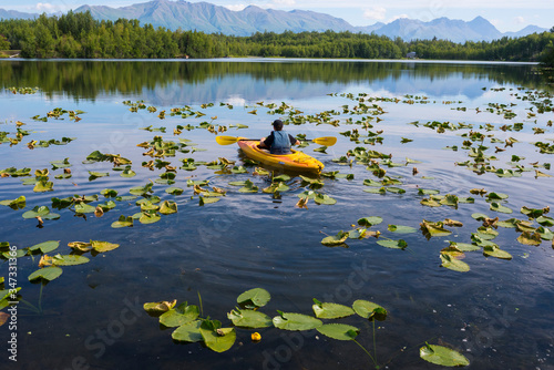 Teenage boy paddles canoe in lily pad-covered lake near Palmer Alaska. photo