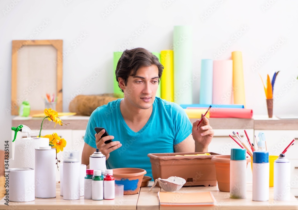 Young man decorating pottery in class Young man decorating pottery in class