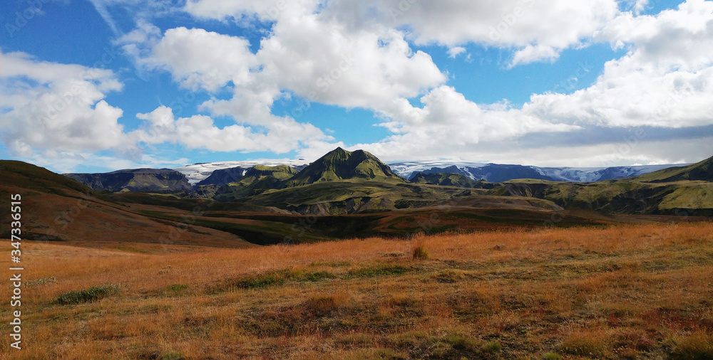 Field, hills, mountain and glacier landscape with blue sky and clouds - Laugavegur trail, Iceland