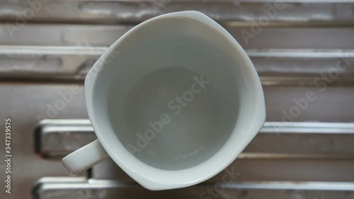 Shallow focus blurred top view of milk tea pouring in to white cup with foam.