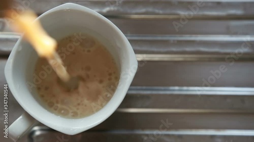 Shallow focus blurred top view of milk tea pouring in to white cup with foam.