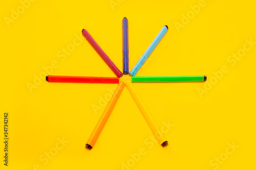 colored markers in rainbow colors on a yellow background