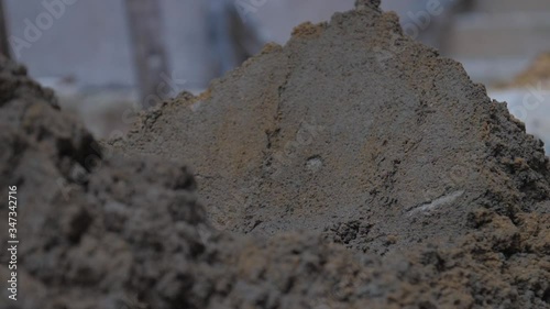 Wallpaper Mural person mixes wet cement with metal shovel on ground against blurry yellow pile slow motion close view. Concept slavery and poverty Torontodigital.ca