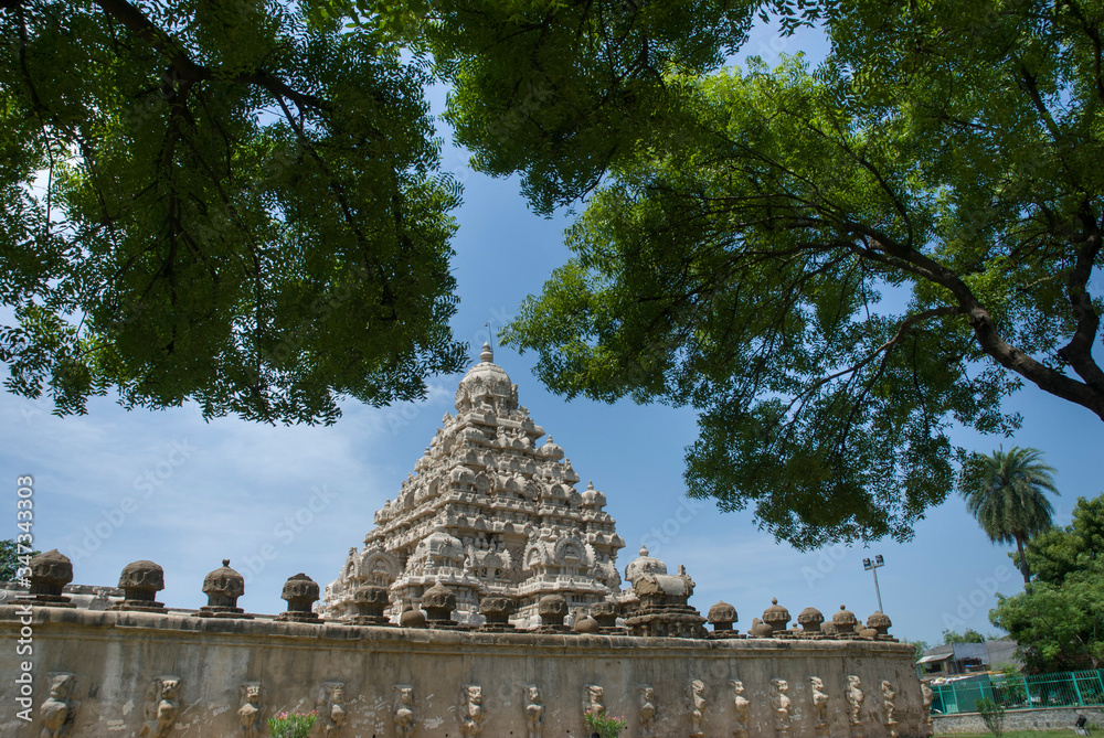 KANCHIPURAM TAMILNADU / INDIA SEP 11 2011 side view of kailasanathar temple gopuram with blue sky background. view of branches of trees above the gopuram KANCHIPURAM TAMILNADU / INDIA SEP 11 2011 side view of kailasanathar temple gopuram with blue sky background. view of branches of trees above the gopuram