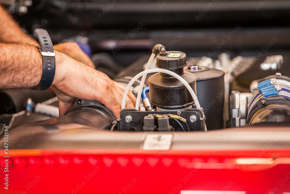 A mechanic is reviewing and repairing the engine and some mechanical parts of a supercar