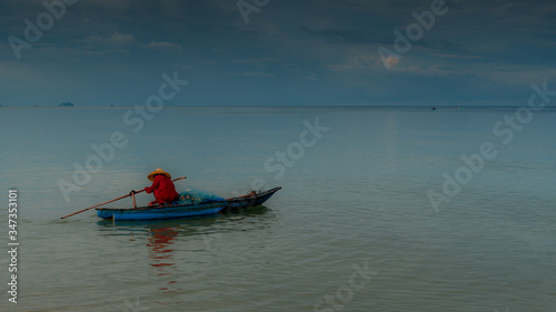 Older man fishing on smal boat in calm seas on the Gulf of Thailand