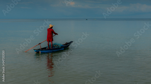 Older man fishing on smal boat in calm seas on the Gulf of Thailand