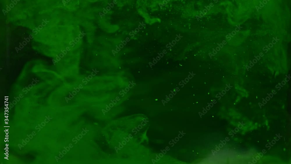 Green paint drops mixing in water slow motion. Smooth ink swirling and splashing from above underwater. Ink cloud on black background. Colored abstract smoke explosion. Green paint drops mixing in water slow motion. Smooth ink swirling and splashing from above underwater. Ink cloud on black background. Colored abstract smoke explosion.