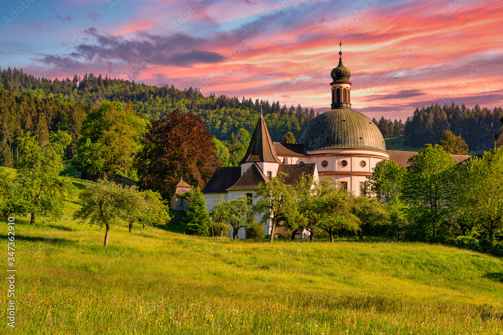 The Benedictine monastery St. Trudpert (Kloster Sankt Trudpert) in the Black Forest in Muenstertal at sunset in front of a colourful sky - obrazy, fototapety, plakaty 