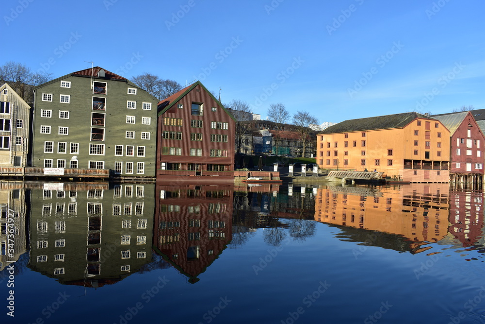 background of colourful storehouse and reflection near Nidelva river T rondheim Norway