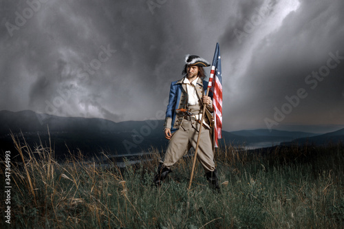 Man in United States War of Independence soldier costume with flag posing in forest. 4th July independence day of USA concept photo