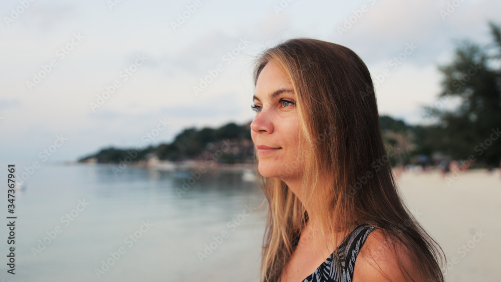Beautiful happy woman enjoying peaceful seaside at sunset time