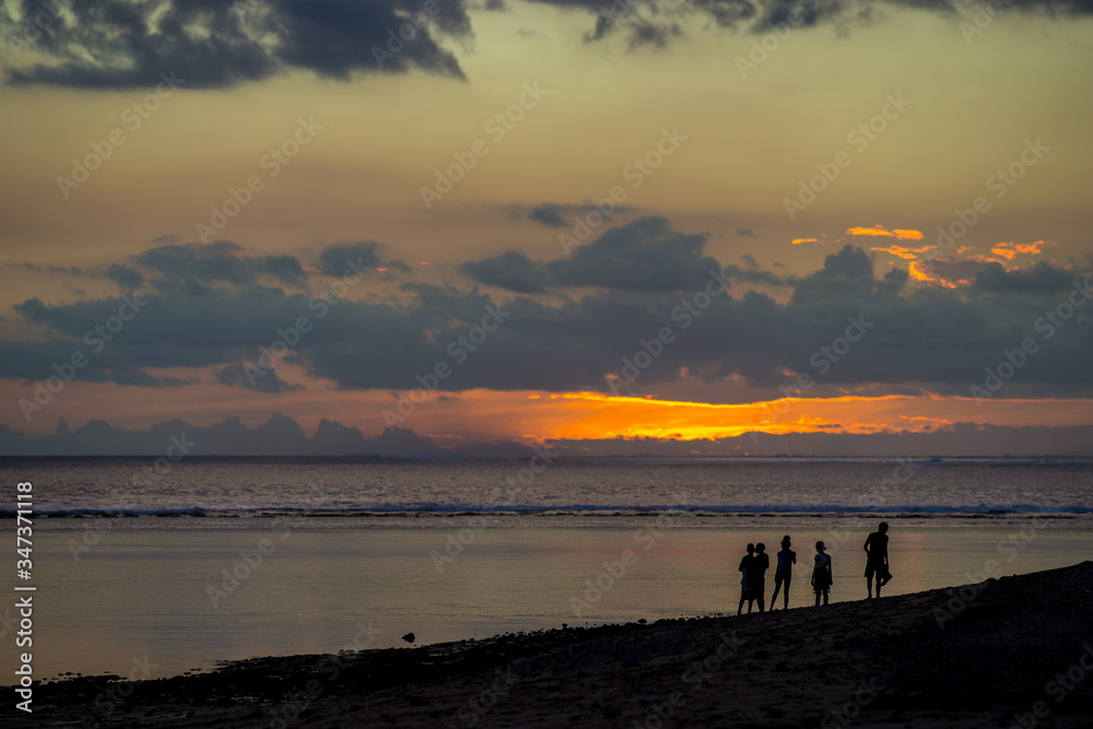 People walk on the ocean against the background of an incredible sunset. Mauritius, Indian Ocean.