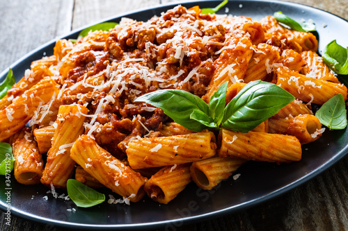 Tortiglioni with tomato sauce, meat and parmesan on wooden background