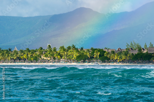 Fototapeta Naklejka Na Ścianę i Meble -  A huge rainbow against the backdrop of picturesque mountains, waves and ocean. Mauritius Island, Indian Ocean