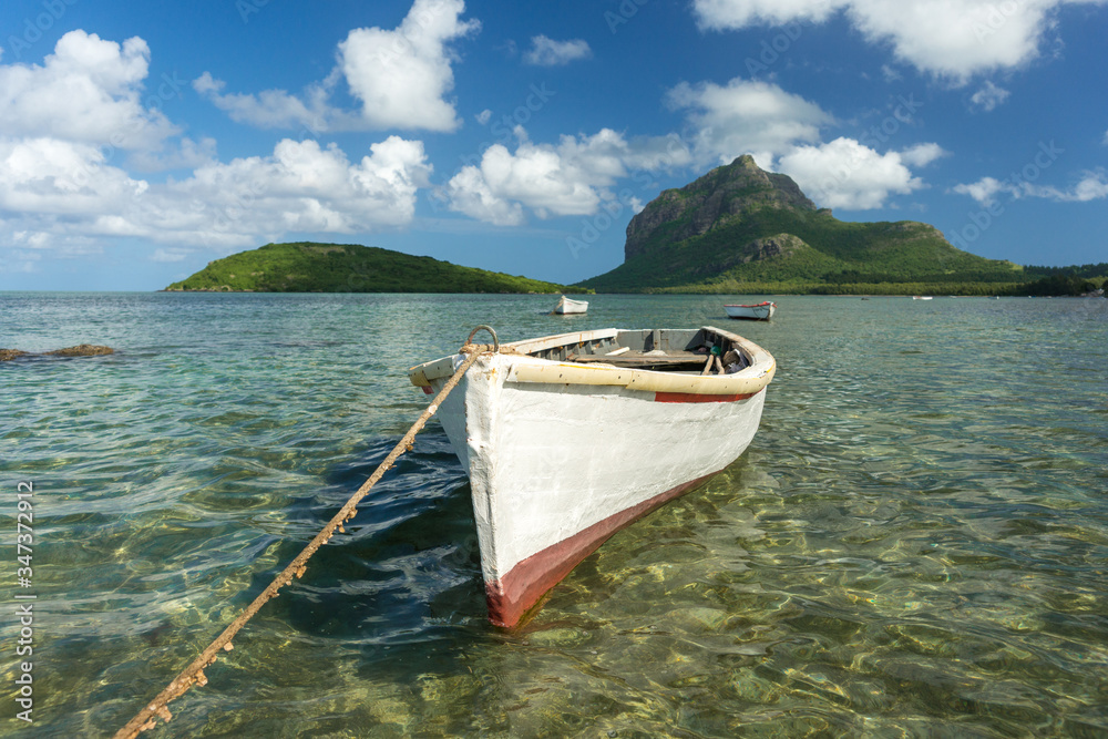 fishing boats against the blue sky, snow-white clouds, mountain and transparent ocean water. Mauritius Island, Indian Ocean