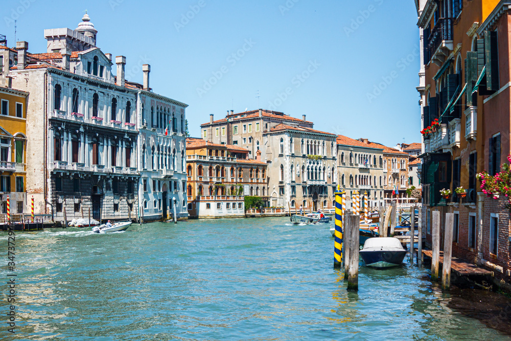 Cityscape of a sunny day on a wide canal with emerald green water in Venice, Italy