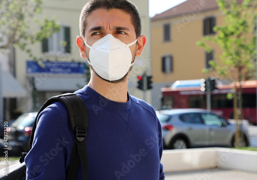 COVID-19 Pandemic Coronavirus Man in city street wearing KN95 FFP2 face mask protective for spreading of Coronavirus Disease 2019. Portrait of man with face mask against SARS-CoV-2.