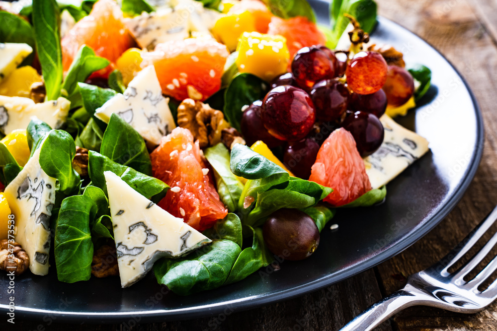 Fresh salad - blue cheese, fruit and vegetables on wooden table
