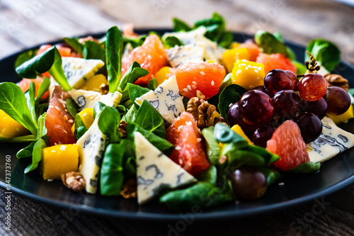 Fresh salad - blue cheese, fruit and vegetables on wooden table 