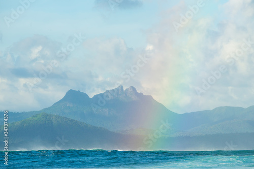 A huge rainbow against the backdrop of picturesque mountains, waves and ocean. Mauritius Island, Indian Ocean © ohrim