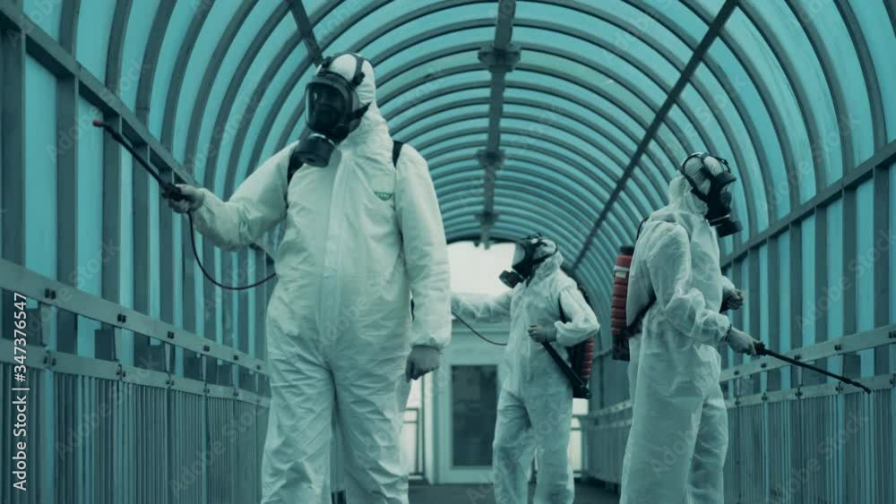 Cleaners in hazmats spray an overpass to kill coronavirus. Cleaners in hazmats spray an overpass to kill coronavirus.