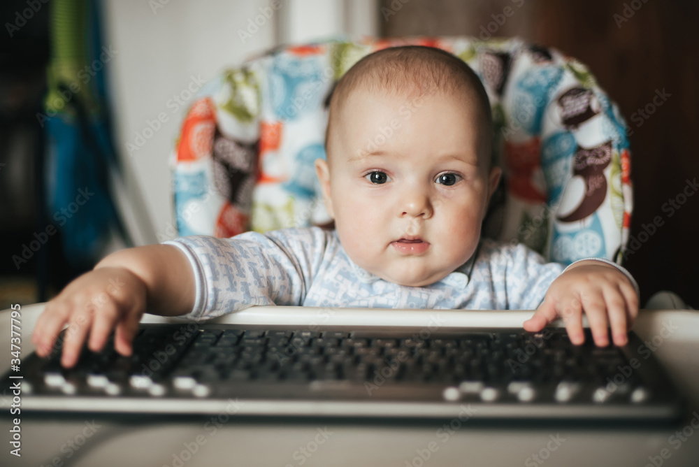 portrait of a cute baby boy sitting and playing with a keyboard portrait of a cute baby boy sitting and playing with a keyboard