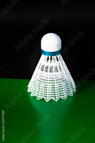 lastic  Badminton shuttlecock. Macro of a plastic  shuttlecock isolated on the green background. Design of a shuttlecock. Badminton accessories. Sports equipment. place for text photo