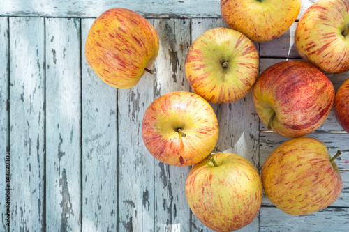 Red apples lie on a white old vintage wooden surface. Place for text on the left