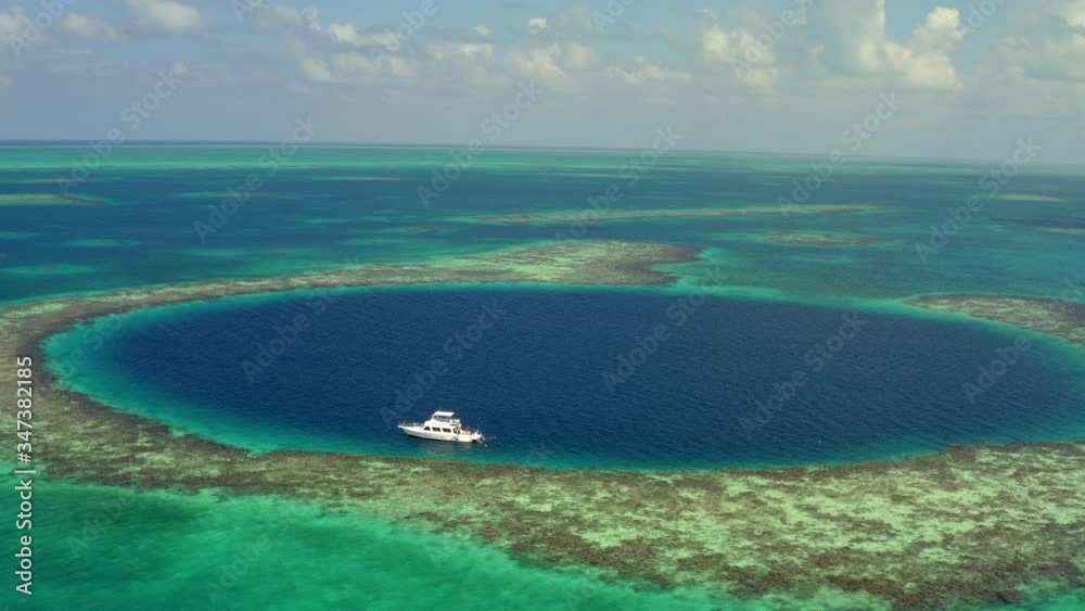 Aerial view of yacht in marine sinkhole against cloudy sky, scenic view of seascape - Great Blue Hole, Belize