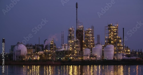 Evening slow motion shot of a chemical factory or a refinery plant with a smoking chimney.
