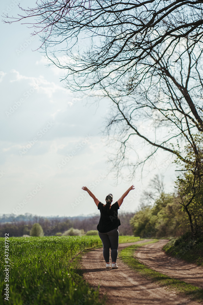 Body positive, success, freedom, happiness, confidence, self esteem. Overweight woman rising hands to the sky. Obesity and outdoor activity Body positive, success, freedom, happiness, confidence, self esteem. Overweight woman rising hands to the sky. Obesity and outdoor activity