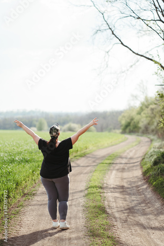 Life goals and achievement. Happy woman standing in nature. Female runner raising arms expressing positivity and success.