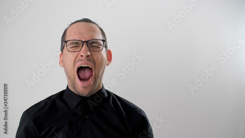 Man in glasses yells out loud from despair during quarantine or yawns violently. Man wide open his mouth. Powerful different emotions. Scream. Man is afraid or wants to sleep