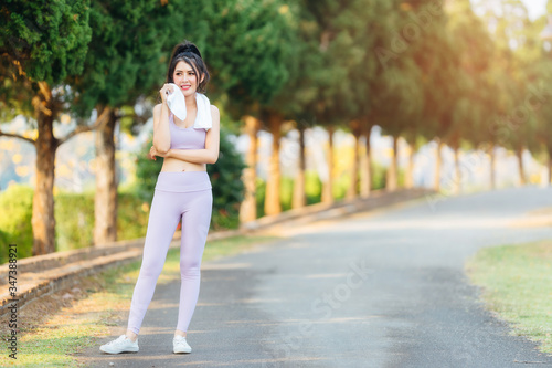 Beautiful Asian woman wearing purple exercise suit running in the park.