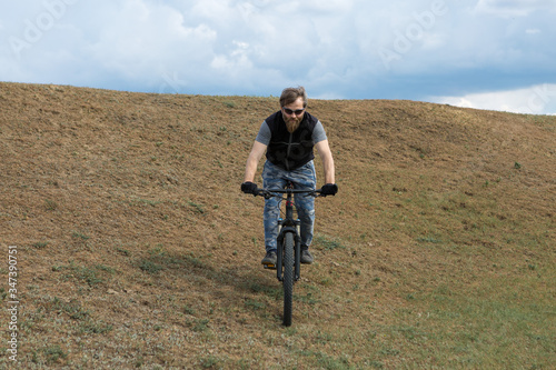 Sports brutal bearded guy on a modern mountain bike. A cyclist in a salt deserted place by the lake.