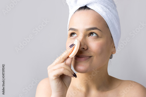 Beauty portrait of woman in white towel on head with a sponge for a body in view of a pink heart. Skincare cleansing eco organic cosmetic spa relax concept.