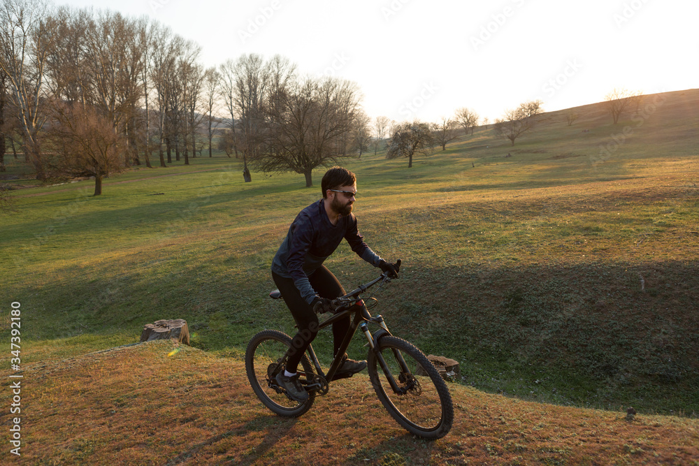 Cyclist in shorts and jersey on a modern carbon hardtail bike with an air suspension fork standing on a cliff against the background of fresh green spring forest Cyclist in shorts and jersey on a modern carbon hardtail bike with an air suspension fork standing on a cliff against the background of fresh green spring forest