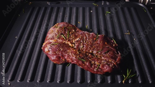 Delicious juicy meat steak toss on the grill. Cook prime rare roast grilling tenderloin fresh marble tenderness beef. Throw beef on electric roaster. Pour salt, rosemary, black pepper. Slow motion. photo