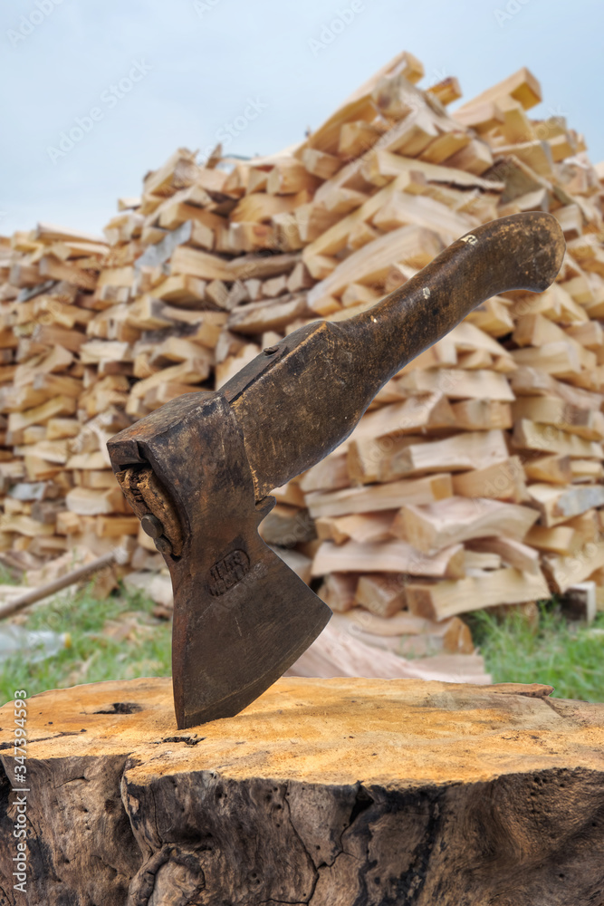 Old rusty axe with wooden handle stuck in the stump. blurred background with firewood Old rusty axe with wooden handle stuck in the stump. blurred background with firewood