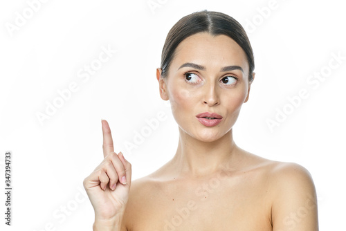 Photo of happy young woman standing isolated over white wall background. Looking camera showing copyspace pointing.